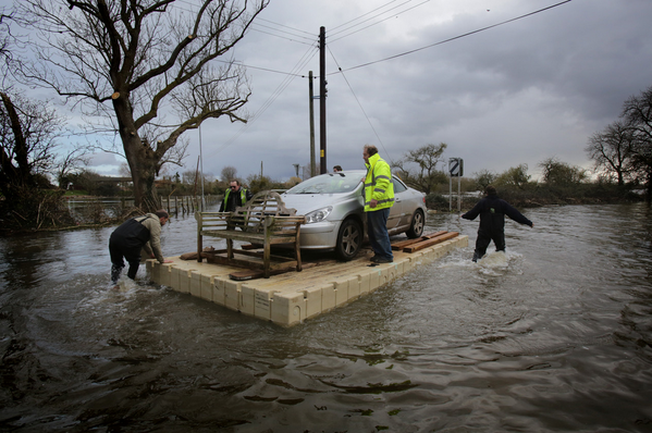 Men use a pontoon to move a car in floodwaters in England. More Photos of the Day: http://t.co/FRtR4mSIQM (Getty) http://t.co/QeaNAsRj0r - embedded image